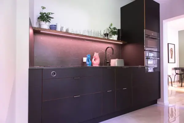 Moderne schwarze Küche mit LED-Beleuchtung, Einbaugeräten und Dekoration.