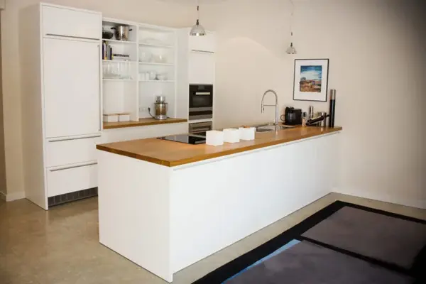 Moderne Einbauküche mit Kochinsel, Holzarbeitsplatte und hellen Küchenschränken.