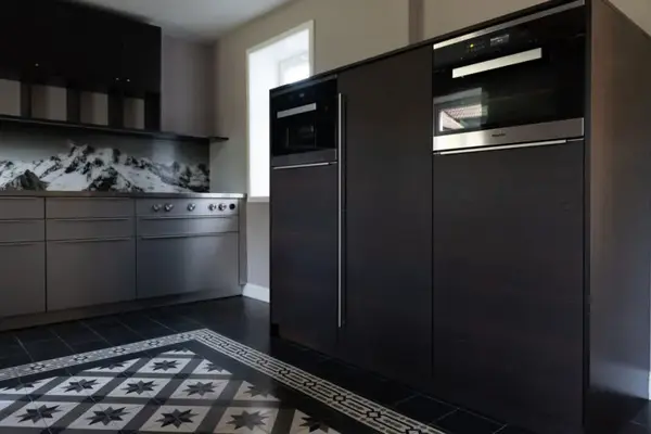 Moderne Küche mit dunklen Fronten, Einbaugeräten und Bergpanorama als Rückwanddekor.