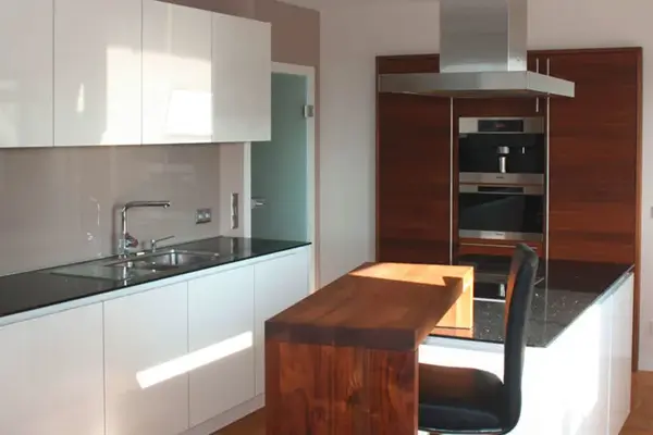 Moderne Einbauküche mit Kochinsel, weißen Hochglanzfronten und Holztheke.