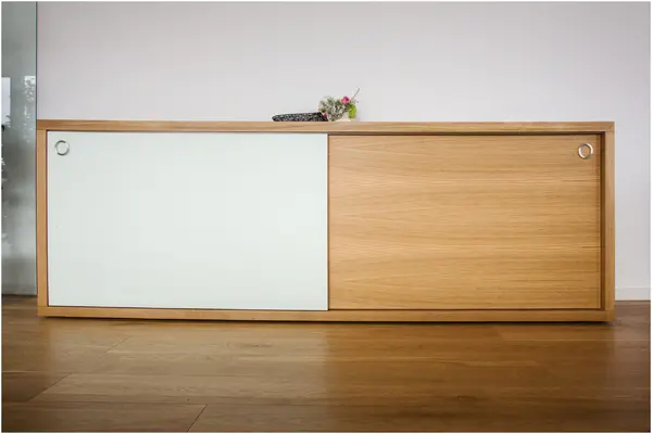 Modernes Sideboard aus Holz mit Schiebetüren und Blumendekoration im minimalistischen Design.
