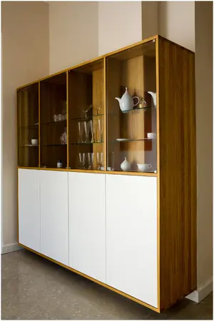 Modernes Sideboard aus Holz mit Glastüren, gefüllt mit Geschirr und Gläsern im Wohnzimmer.