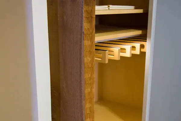 Offener Holzschrank mit Regalböden und integriertem Flaschenhalter aus Holz.