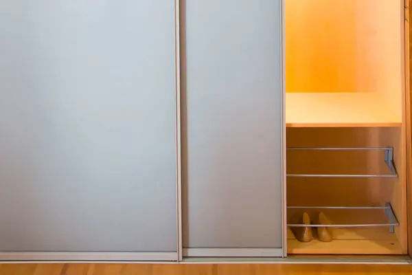 Moderner Kleiderschrank mit Schiebetüren und integriertem Schuhregal aus Holz.