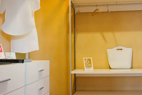 Modernes Ankleidezimmer mit weißem Regal, Kleiderbügeln und Designpreis-Auszeichnung.