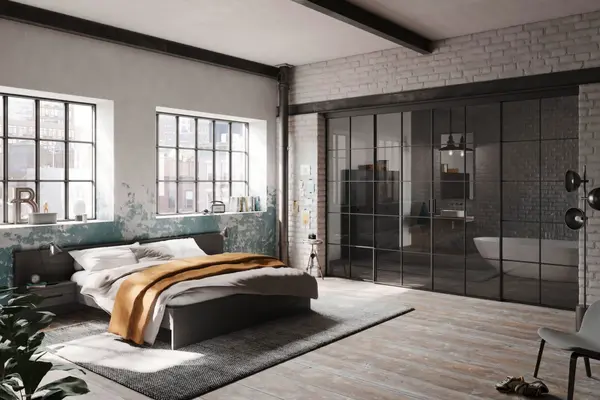 Modernes Schlafzimmer im Industrial Style mit großen Fenstern und Glaswand zum Badezimmer.