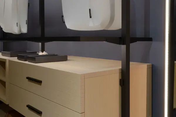 Moderne Kommode aus hellem Holz mit schwarzen Griffen in einem stilvollen Schlafzimmer.