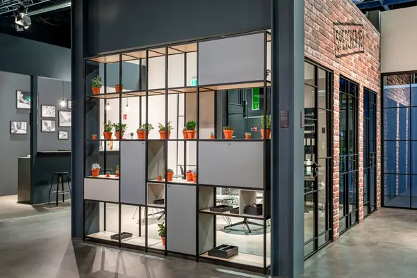 Modernes Büro mit Raumteiler aus Regalen und vielen kleinen Zimmerpflanzen in Töpfen.