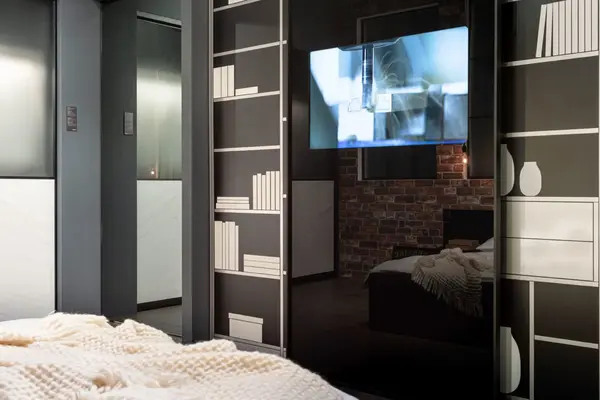 Modernes Schlafzimmer mit Spiegeltürenschrank, Bücherregal-Design und gemütlicher Decke.