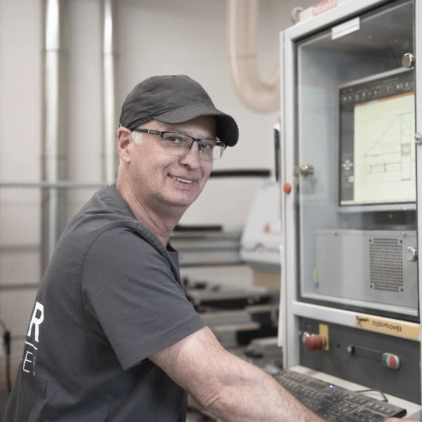 Mitarbeiter an CNC-Maschine in Werkstatt bedient Steuerung am Monitor.